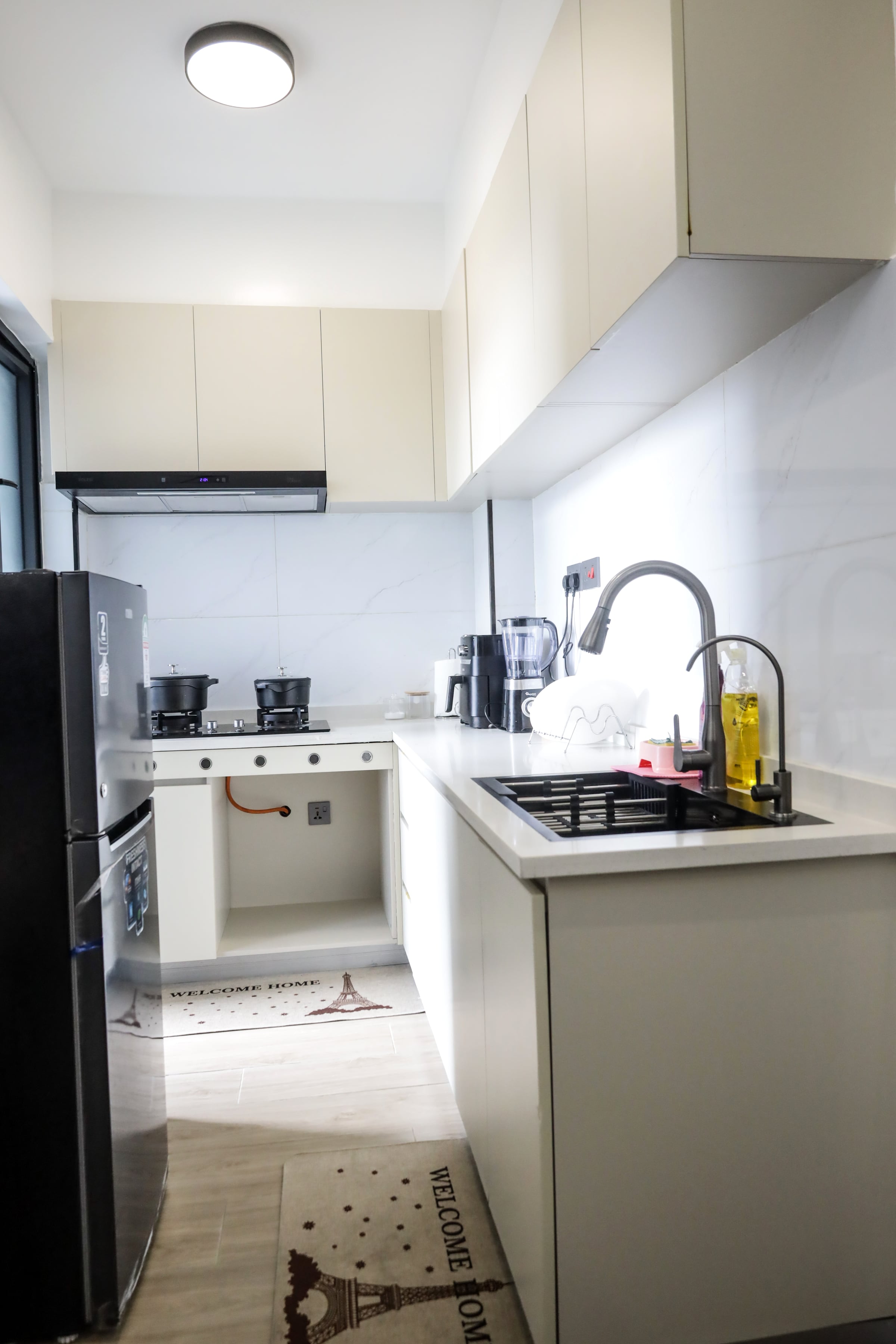 Compact white kitchen with a gas cooktop, coffee maker and stainless sink under a window
