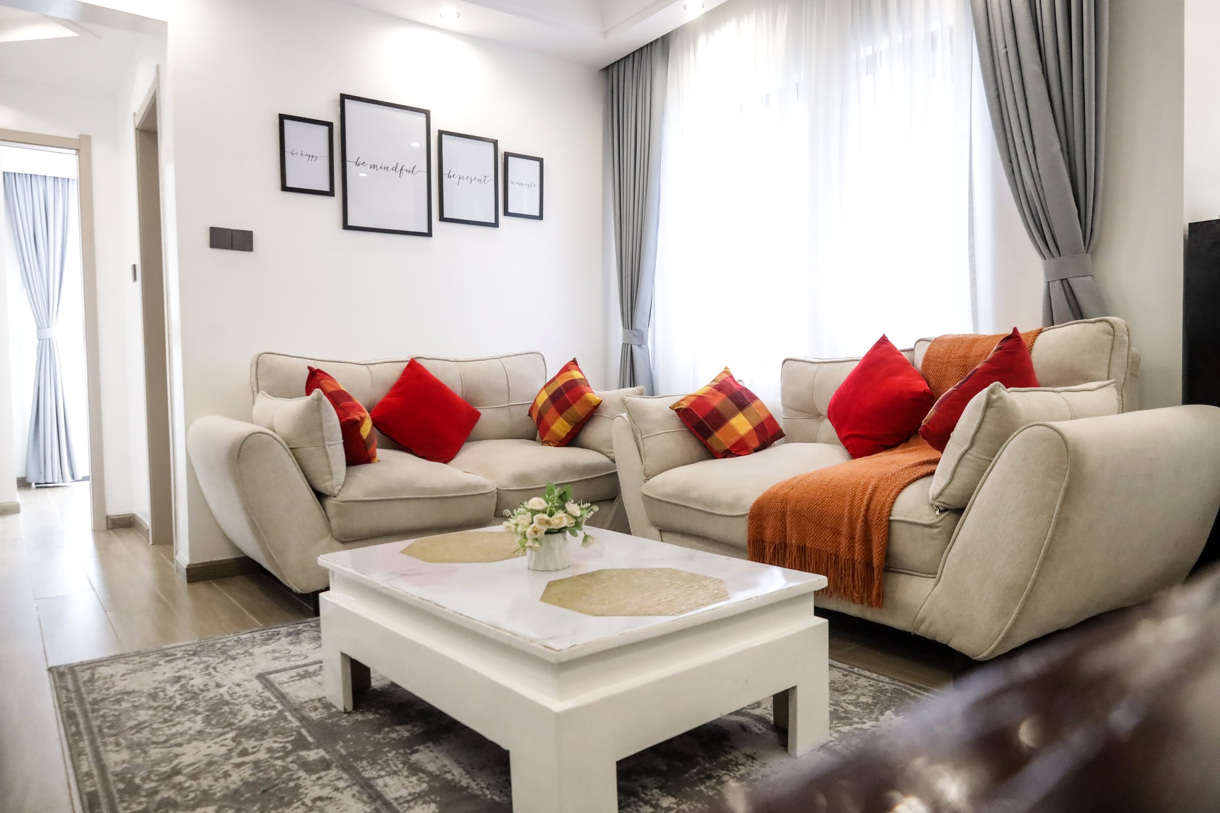 Open living room with two cream sofas, a white coffee table and red and terracotta cushions